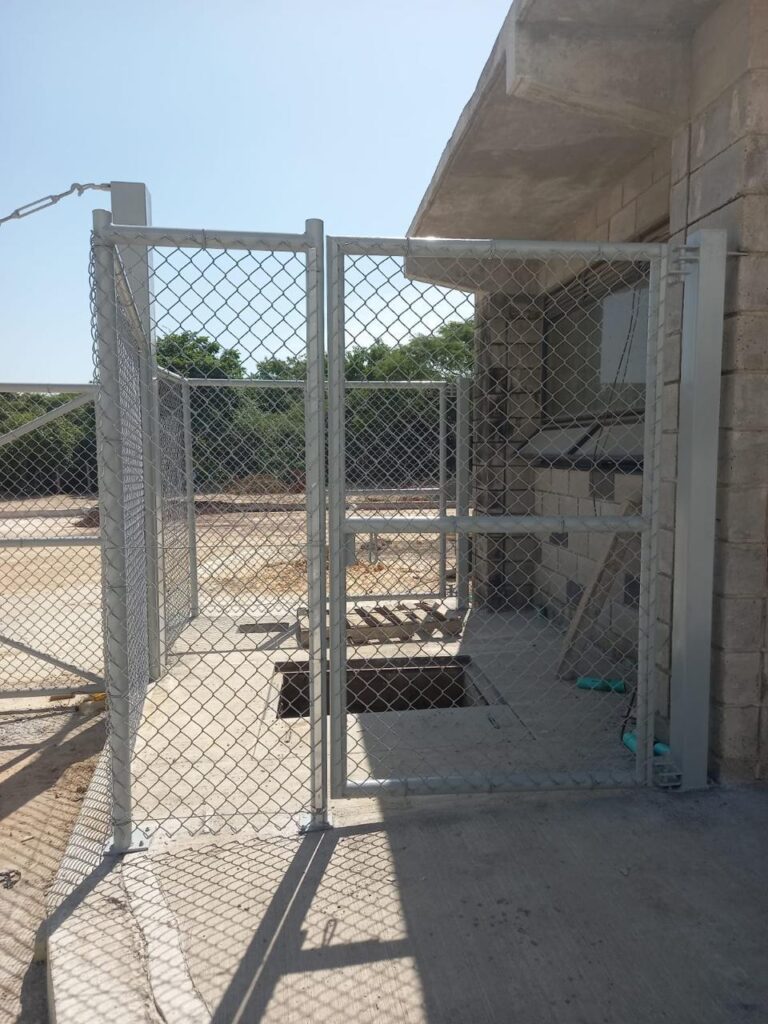 Portón de malla eslabonada y estructura metálica en obra